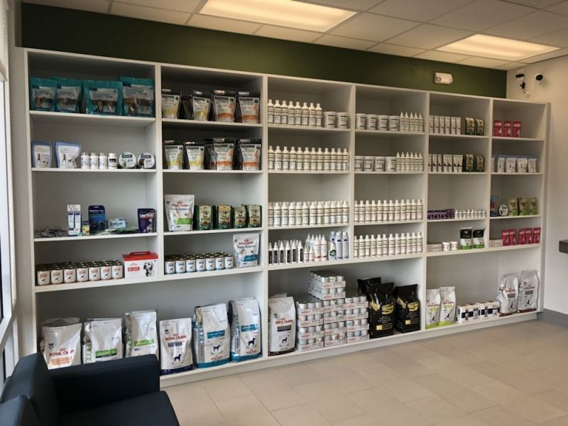 Shelves filled with various pet products, including food bags, bottles, and treat packages in a pet store.